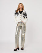 Woman wearing a patterned fairisle button down knit cardigan and silver pants