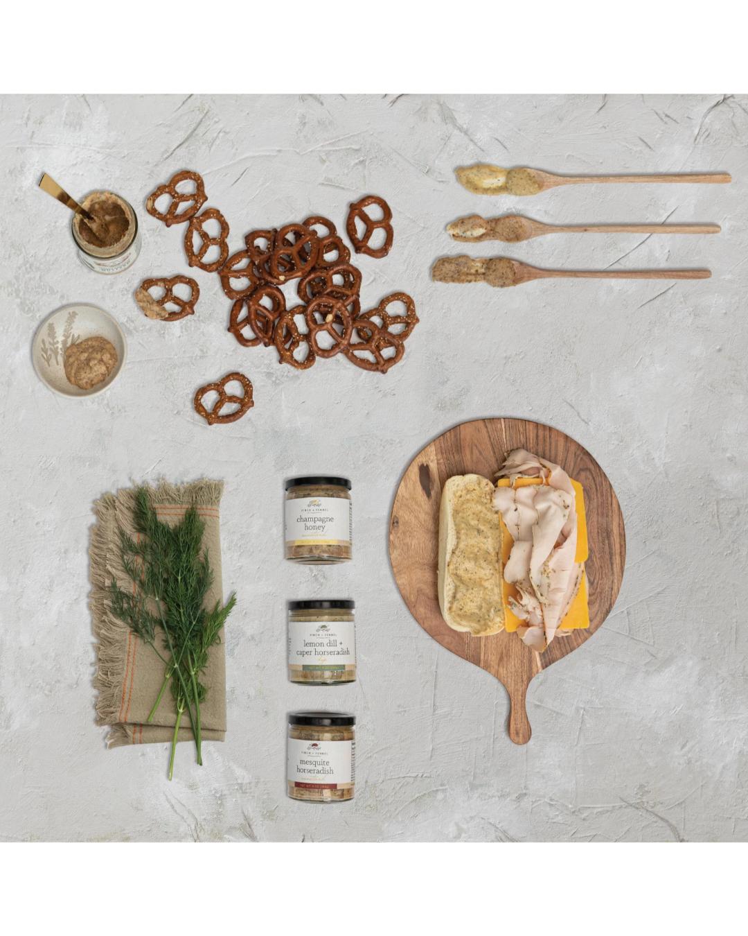 Assorted food items including pretzels, bread with cheese, and jars on a textured surface.