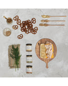 Assorted food items including pretzels, bread with cheese, and jars on a textured surface.
