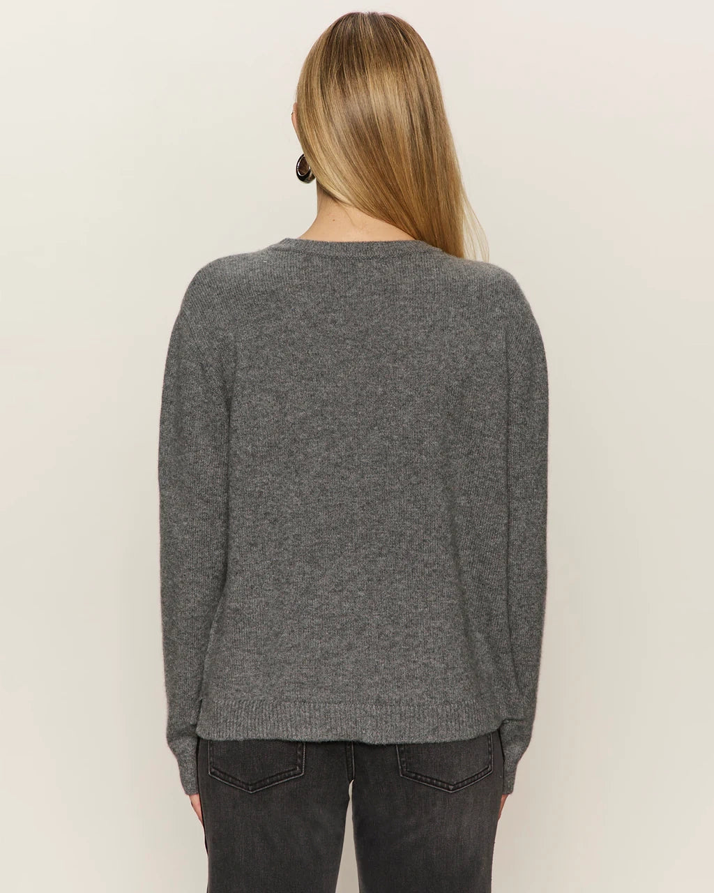 Woman wearing a gray cashmere sweater with 'cheers' text on it
