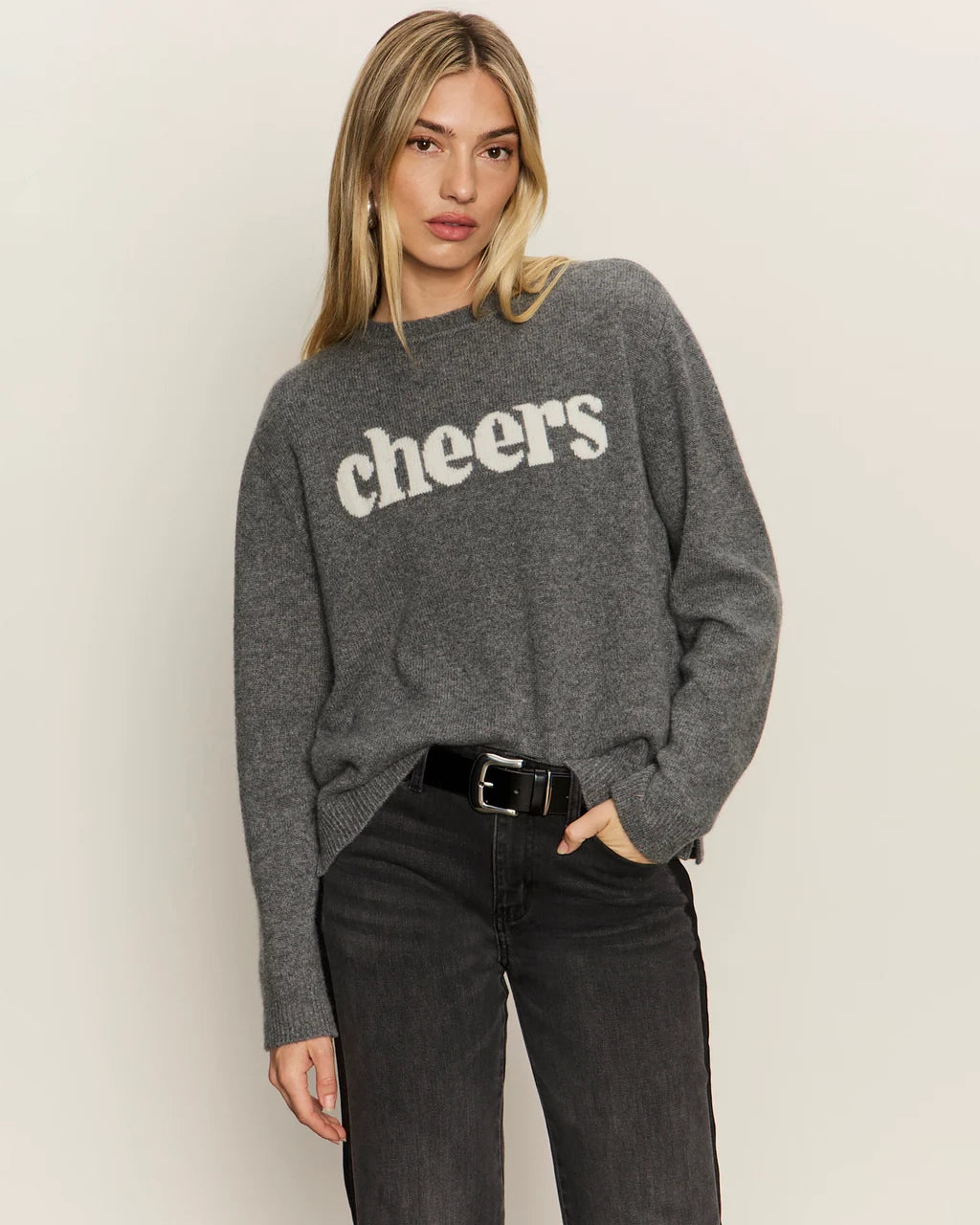 Woman wearing a gray cashmere sweater with 'cheers' text on it