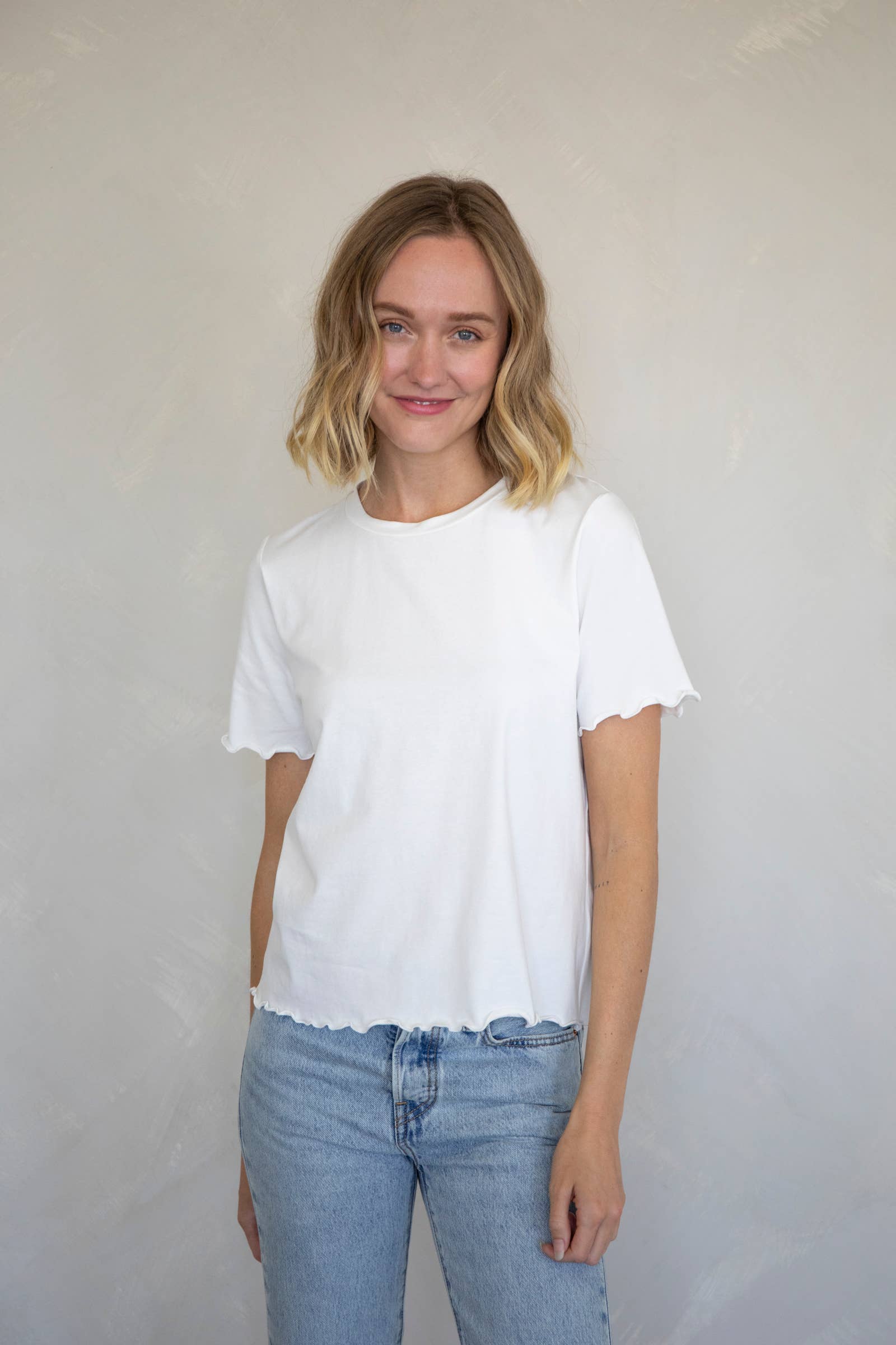 white t-shirt that has a wavy look on the bottom of the shirt and sleeves