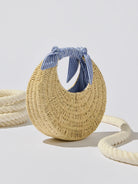 hand bag made out of straw with blue striped ties on the handle