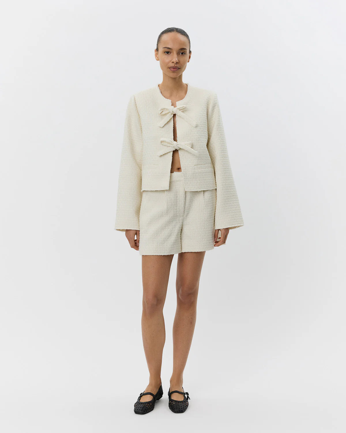 an off white jacket with two large bows tying it together
