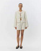 an off white jacket with two large bows tying it together