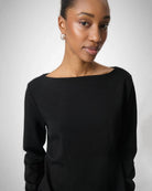 Woman wearing a black long-sleeve top with a boat neckline