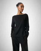 Woman wearing a black long-sleeve top with a boat neckline