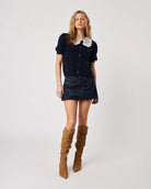 woman wearing navy blue button down cardigan sweater with lace peter pan collar on it in white and brown knee-high boots