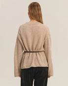 Woman wearing a beige knit cardigan with a thin belt