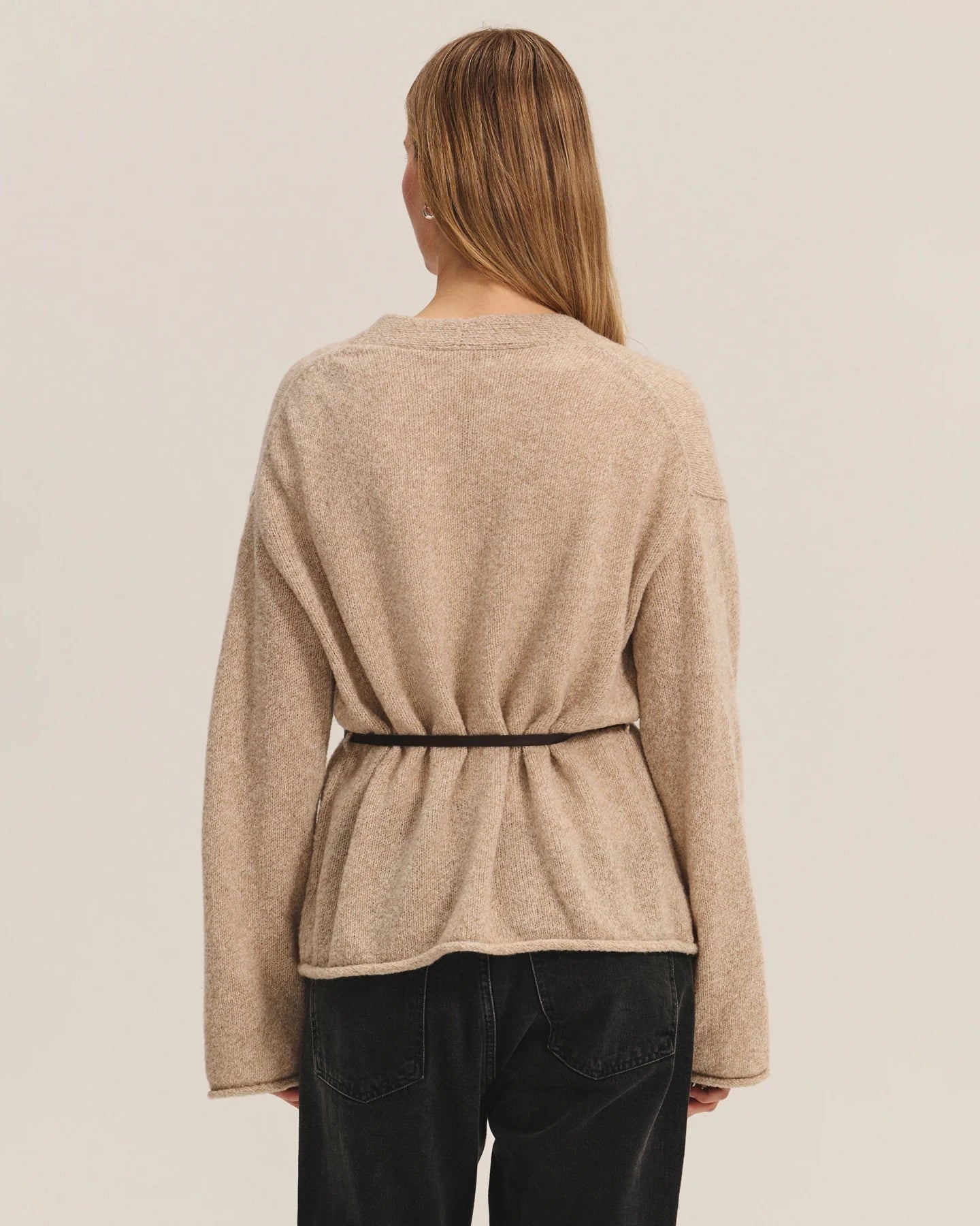Woman wearing a beige knit cardigan with a thin belt