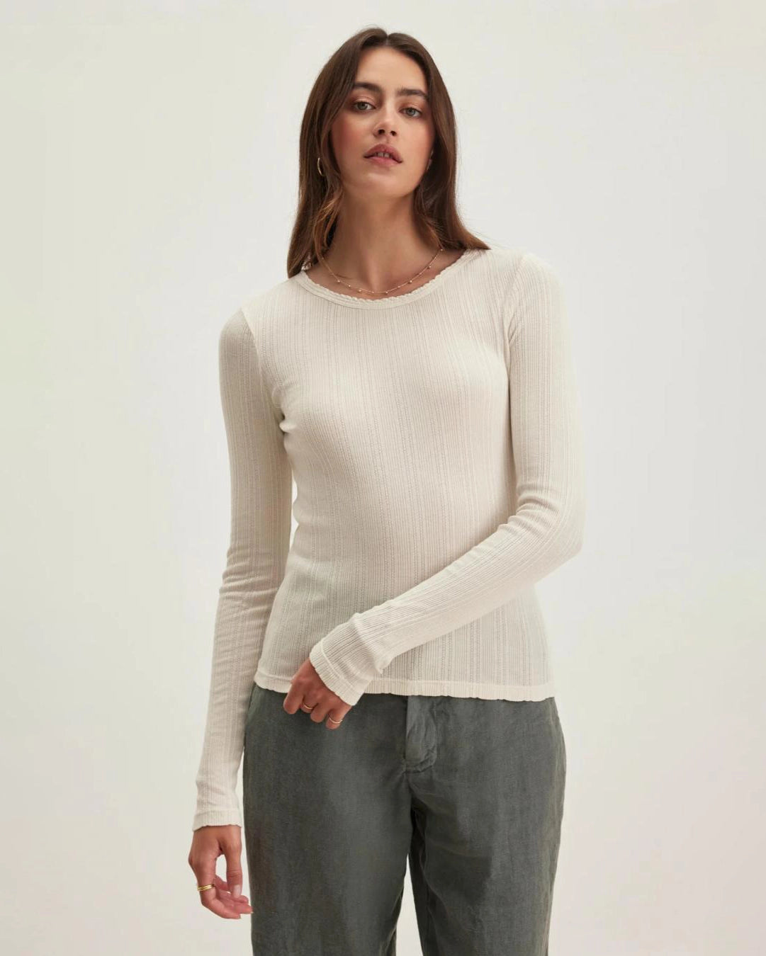 Woman wearing a beige long-sleeve pointelle top 