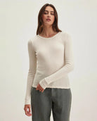 Woman wearing a beige long-sleeve pointelle top 