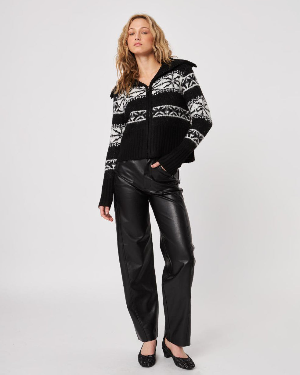 woman wearing a zip up black fairisle cardigan sweater with white pattern and leather pants