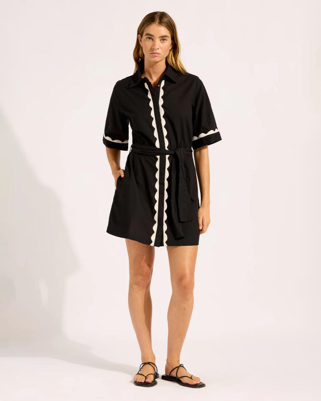 Woman wearing a black cotton t-shirt button down dress with white scalloped trim 