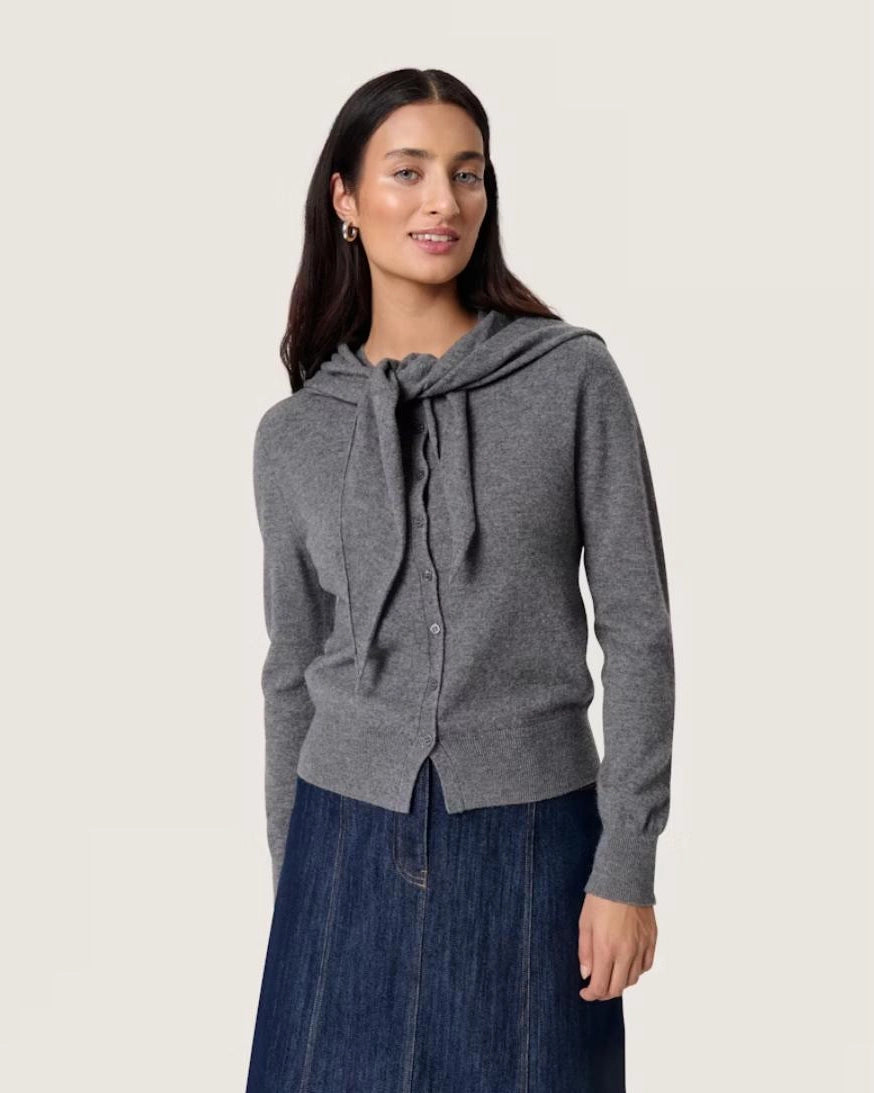 Woman wearing a grey button down cardigan sweater with a tie front scarf design 