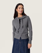 Woman wearing a grey button down cardigan sweater with a tie front scarf design 