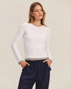 Woman wearing a white long-sleeve top and navy pants