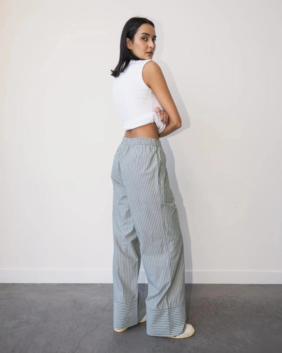 a woman wearing light green striped cotton pants with an elastic waist and buttons with wide hem cuff