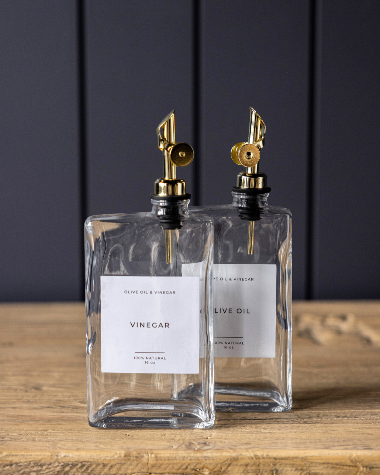 two rectangular glass bottles that dispense olive oil or vinegar