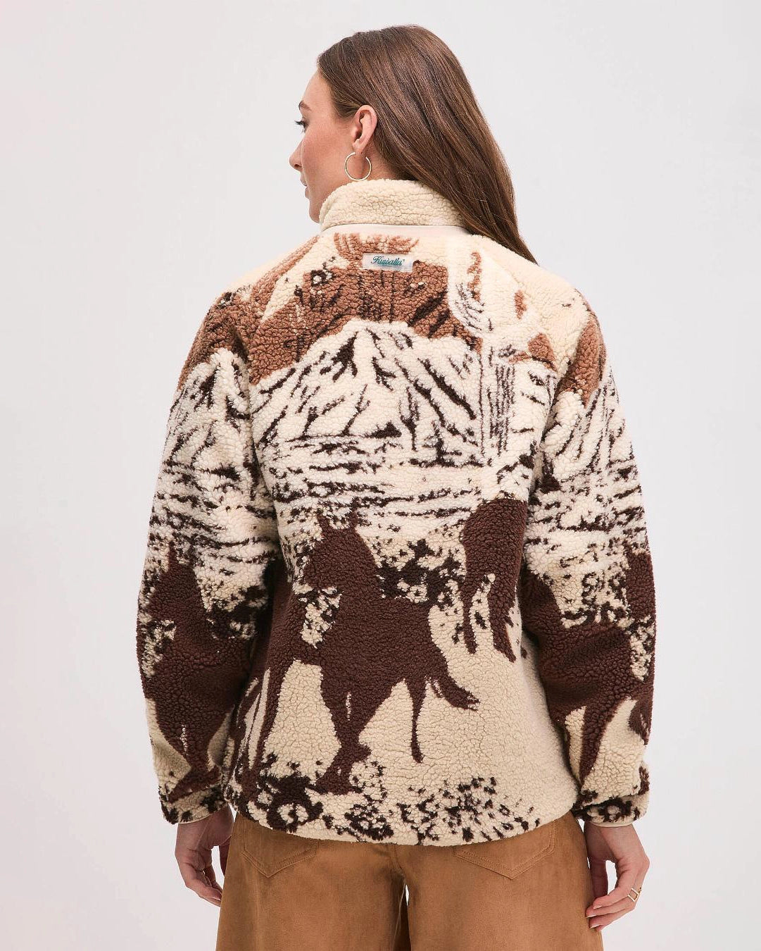 Woman wearing a patterned jacket with horse design in brown and beige