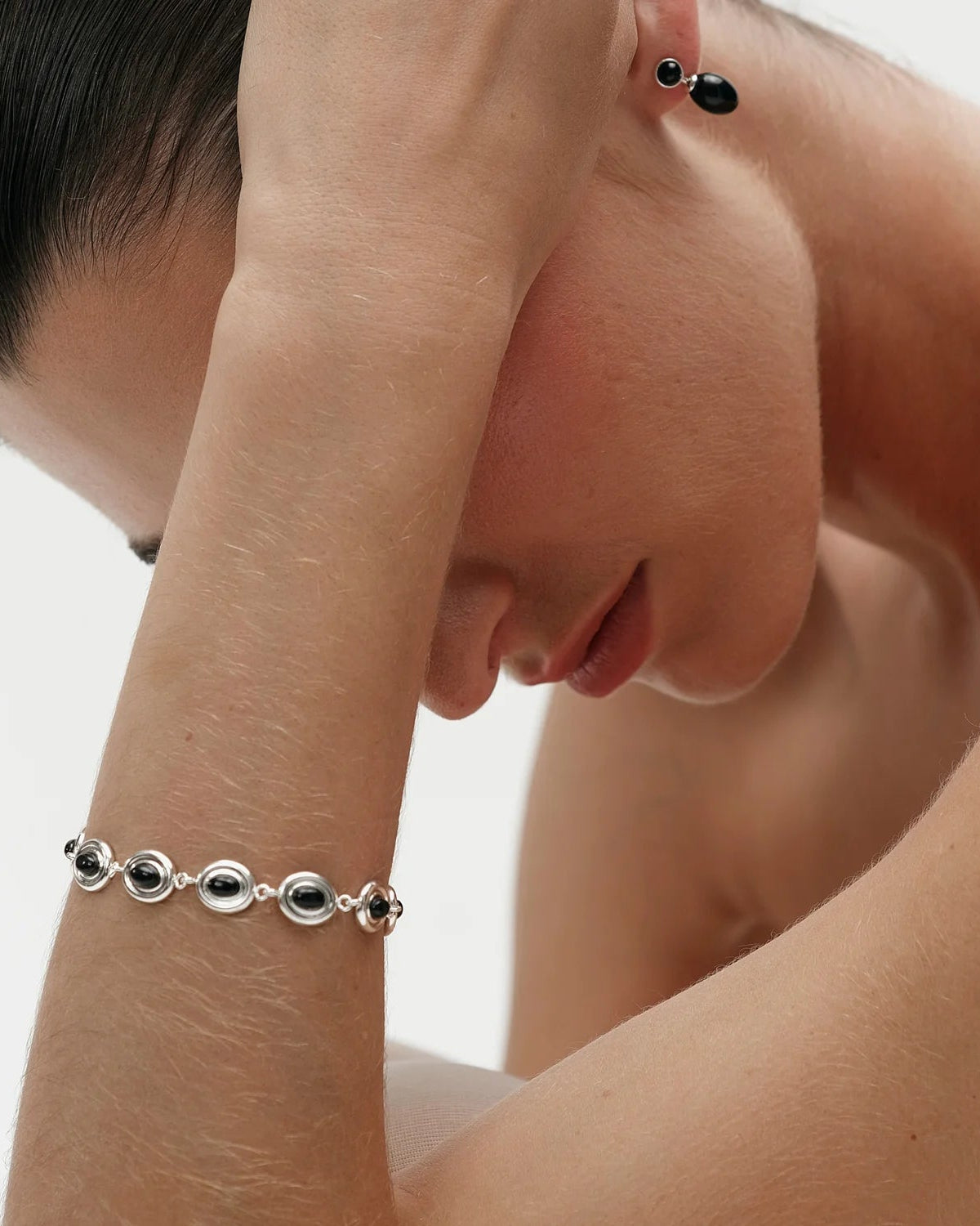 silver oval charm bracelet with black stone in the middle