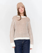 Woman wearing a striped knit beige and white sweater