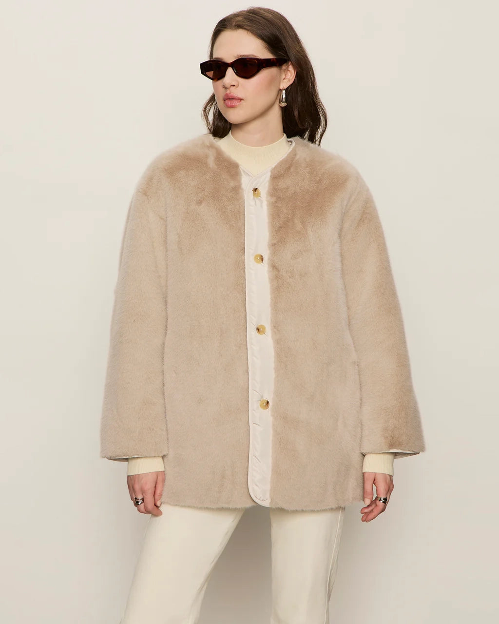 Woman wearing a beige faux fur coat with gold buttons