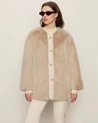 Woman wearing a beige faux fur coat with gold buttons