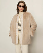 Woman wearing a beige faux fur coat with gold buttons