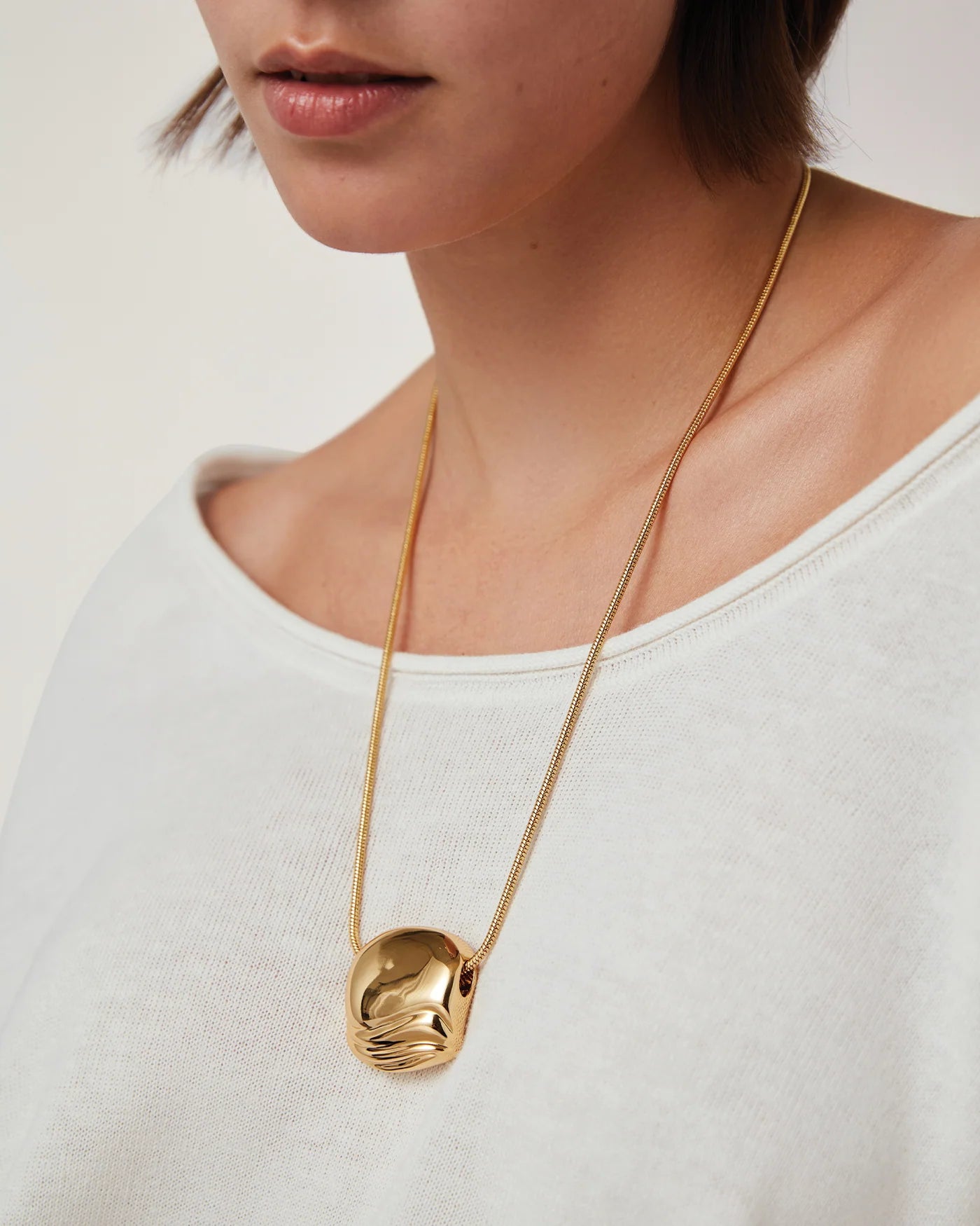 necklace with a statement gold pendant on a long thick gold chain