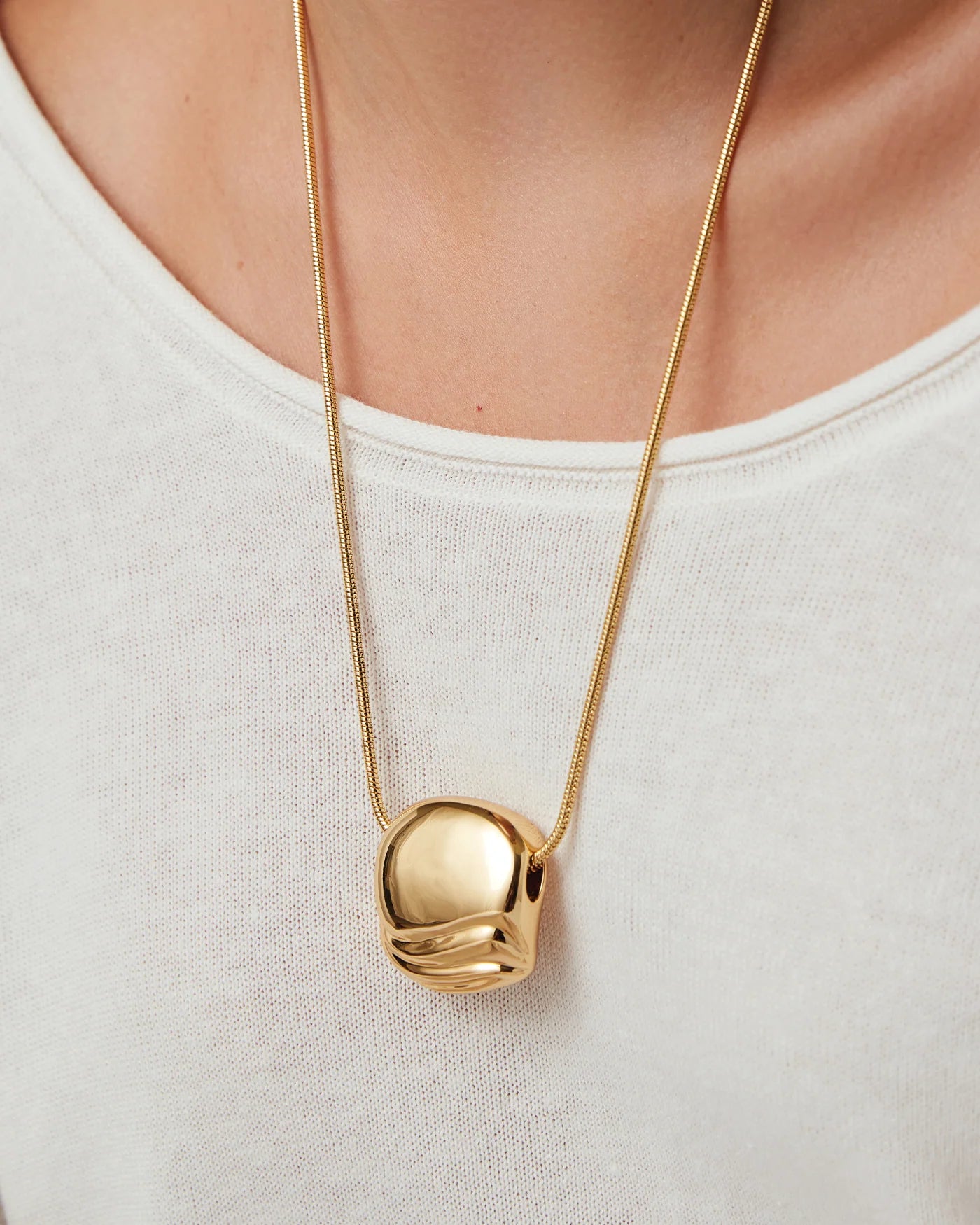 necklace with a statement gold pendant on a long thick gold chain