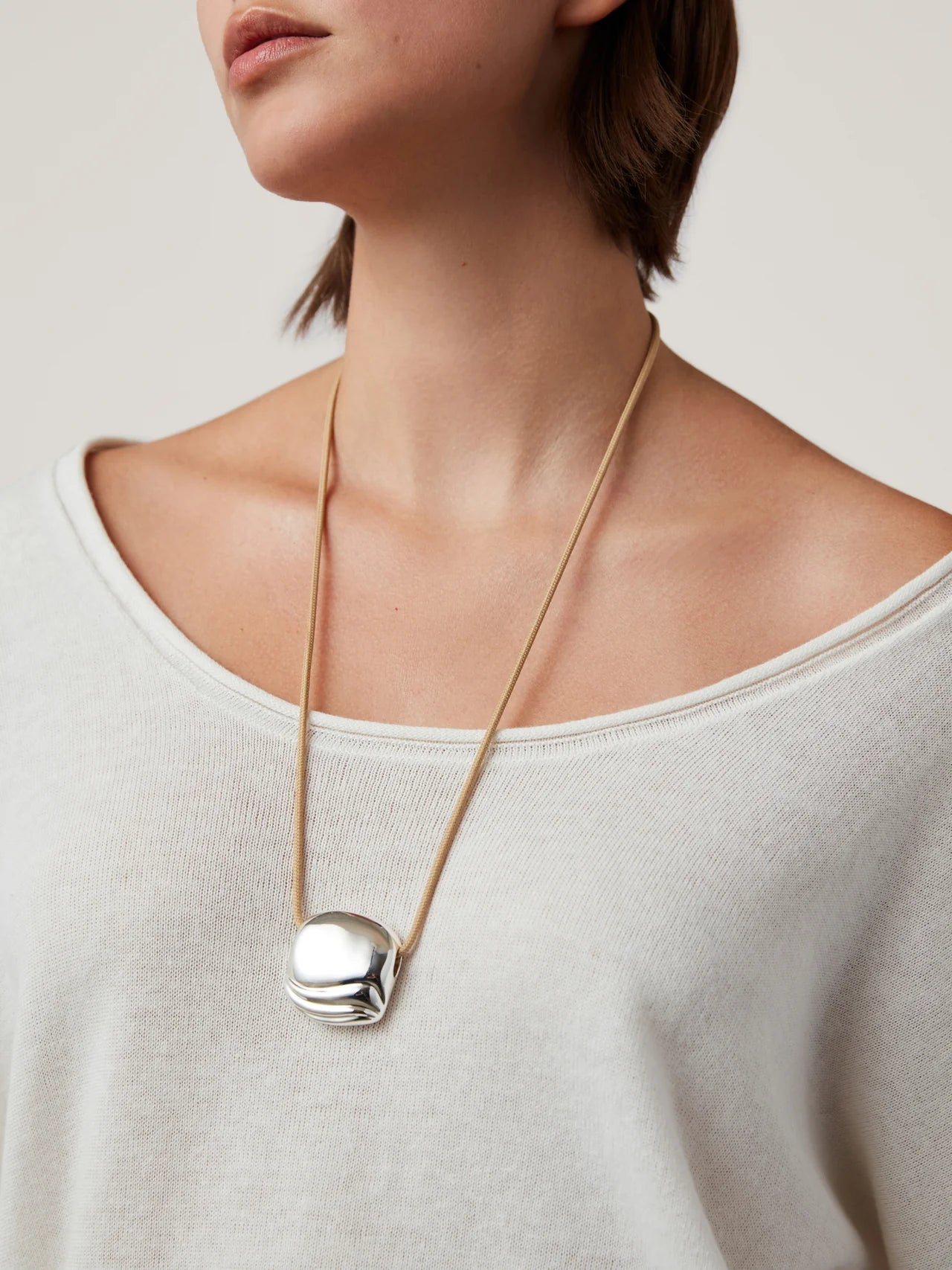 necklace with a statement silver pendant on a tan rope string