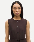 Woman wearing a brown sleeveless button down dress with a belt