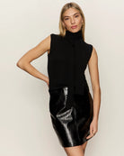 Woman wearing a black sleeveless sweater with scarf detail