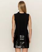 Woman wearing a black sleeveless sweater with scarf detail