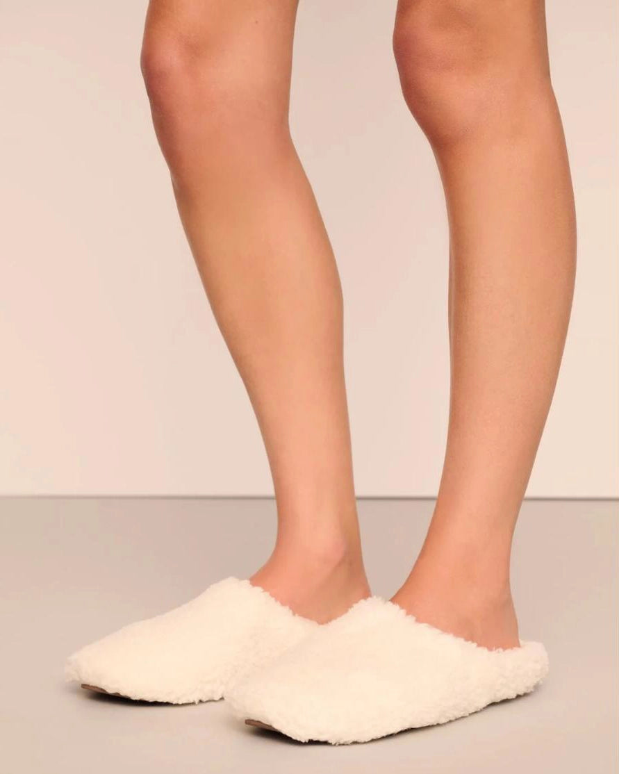 White fluffy sherpa slippers on feet