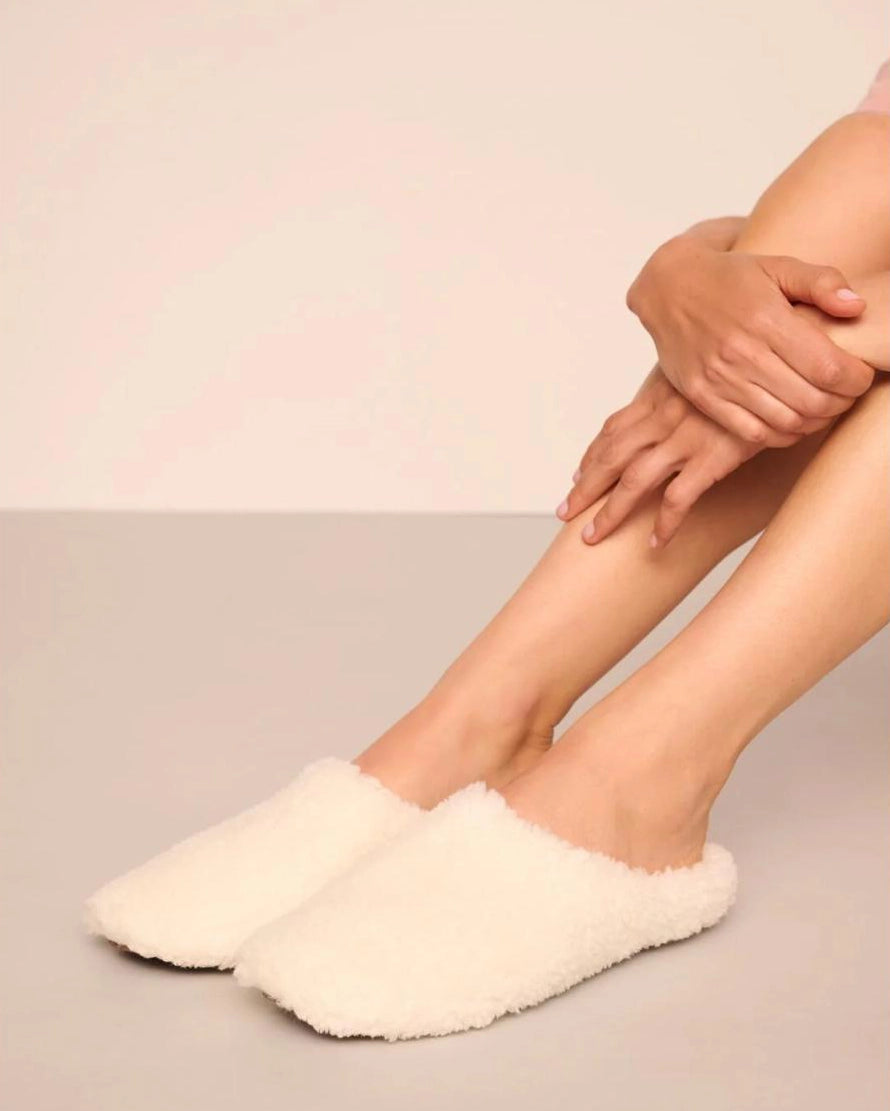 White fluffy sherpa slippers on feet