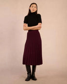 Woman wearing a black turtleneck tee sweater and maroon skirt