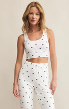 Woman wearing a white tank top and pants with star patterns on a beige background