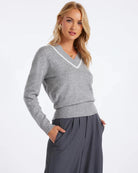 Woman wearing a v neck knit sweater in grey with white trim