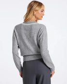 Woman wearing a v neck knit sweater in grey with white trim