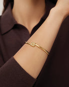 gold slim bangle with a woven design pendant 