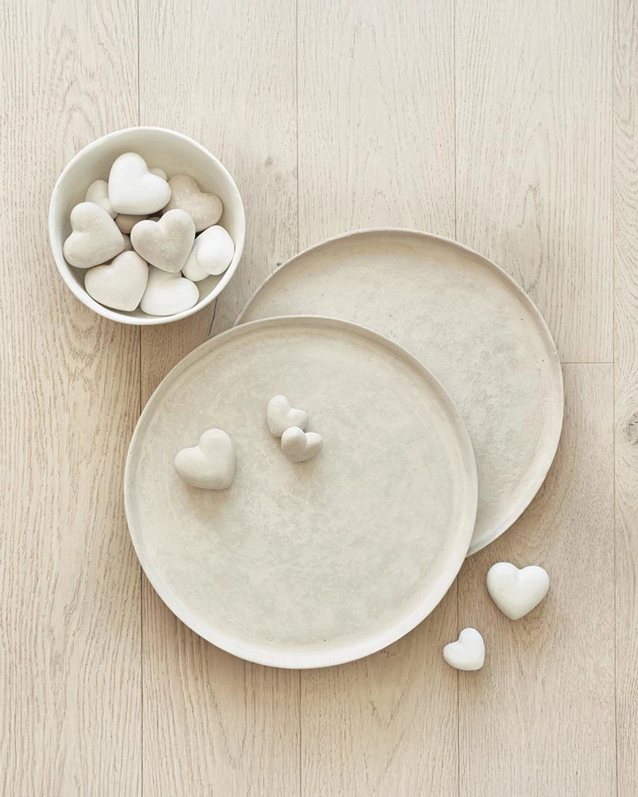 small paper mache hearts in white on top of serving trays and in a bowl
