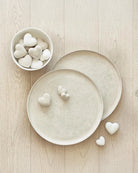 small paper mache hearts in white on top of serving trays and in a bowl