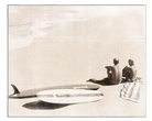 a picture of two people at the beach with a surf board beside them
