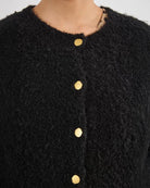 Woman wearing a black fluffy cardigan with gold buttons