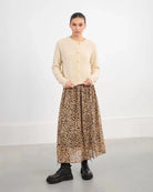 Woman wearing a beige fluffy cardigan with gold buttons and cheetah skirt