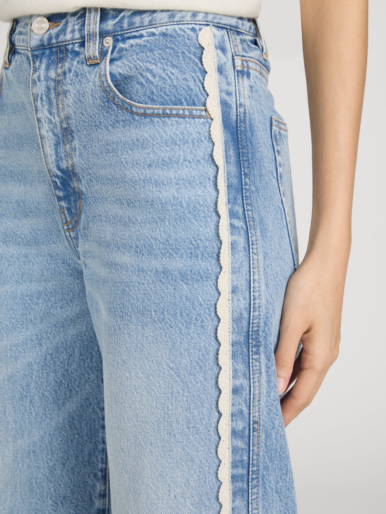 cropped light wash denim pant with a cream crochet detail on the sides 