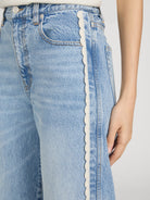 cropped light wash denim pant with a cream crochet detail on the sides 