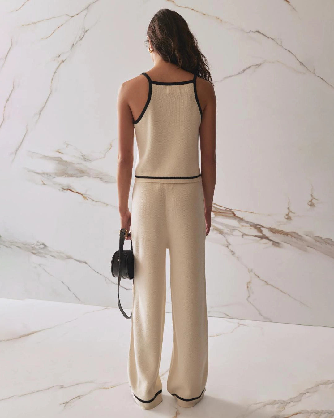 Woman wearing a beige tank top and pants with black trim and matching pants